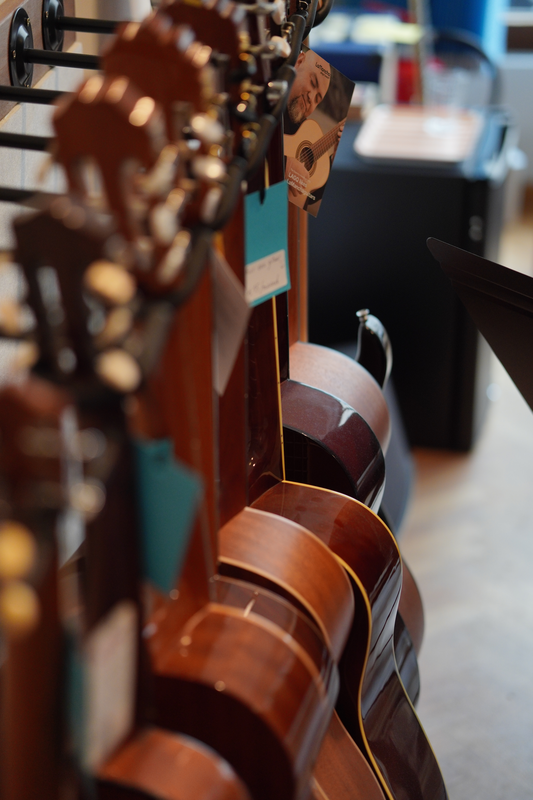 Verschillende gitaren die naast elkaar hangen in close-up.